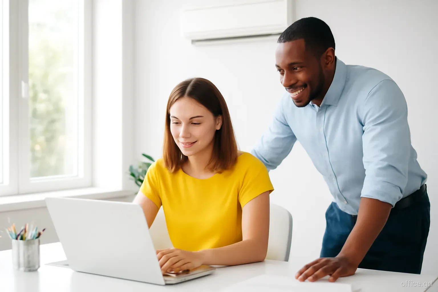 Office manager reviewing a payment run on a laptop with the business owner beside her in a small air-conditioned office in Grenville, side angle, natural window light